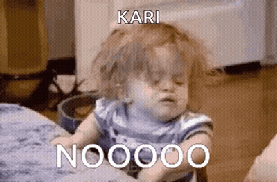 A Baby Is Sitting On A Bed And Making A Funny Face While A Person Holds It . GIF