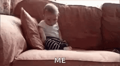 A Baby Is Sitting On A Couch Looking At A Cell Phone And Saying `` Me '' . GIF