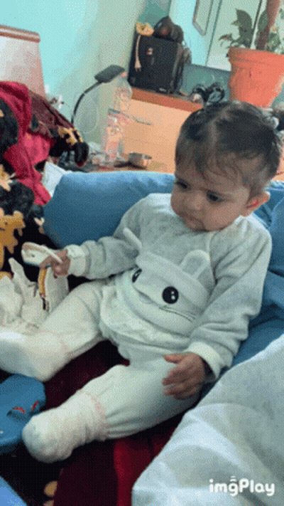 A Baby Is Sitting On A Couch With A Cat On His Shirt GIF