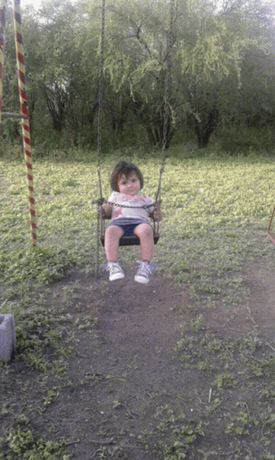 A Baby Is Sitting On A Swing In A Field GIF