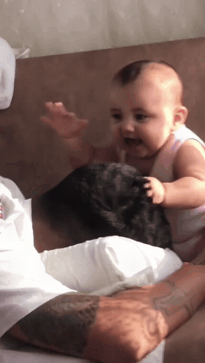A Baby Is Sitting On The Lap Of A Man GIF