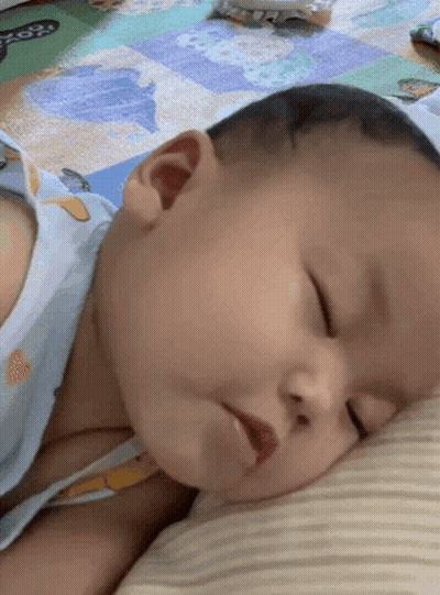A Baby Is Sleeping On A Pillow On The Floor GIF