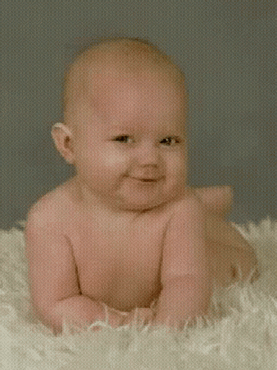 A Baby Is Smiling While Laying On A Fluffy Blanket GIF