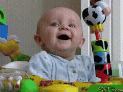 A Baby Is Smiling While Sitting In A Crib With Toys And The Website 4Gifs.com Is Visible In The Corner GIF