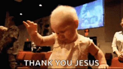 A Baby Is Standing In Front Of A Sign That Says Thank You Jesus . GIF