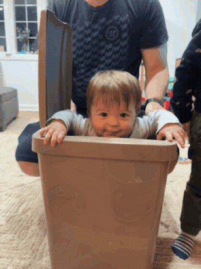 A Baby Is Sticking Its Head Out Of A Trashcan GIF