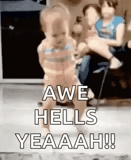 A Baby Is Walking In A Room With A Woman Holding It . GIF