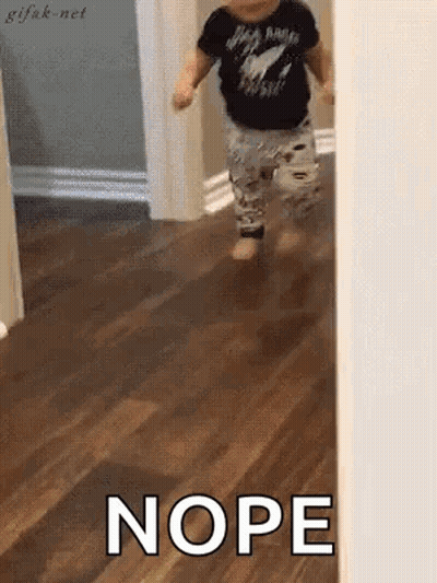 A Baby Is Walking On A Wooden Floor And The Word Nope Is Written On The Floor . GIF