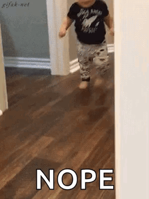 A Baby Is Walking On A Wooden Floor With The Words Nope Written On The Floor . GIF