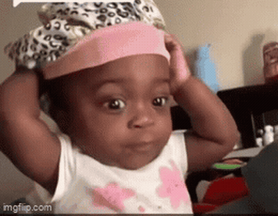 A Baby Is Wearing A Pink Hat And Making A Funny Face GIF