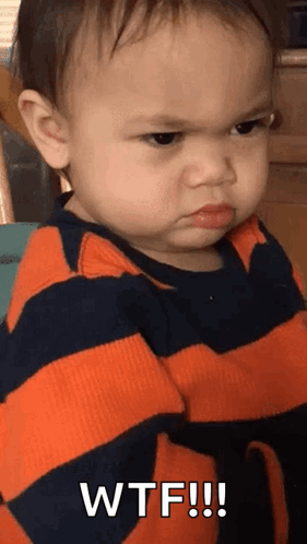 A Baby Is Wearing A Striped Shirt And Making A Funny Face . GIF