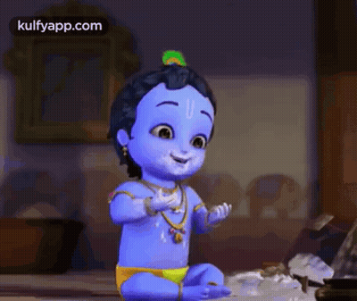 A Baby Krishna With A Peacock Feather On His Head Is Sitting On A Bed Talking On A Cell Phone . GIF