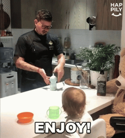 A Baby Sitting At A Table With A Bottle Of Jack Daniel 'S In The Background GIF