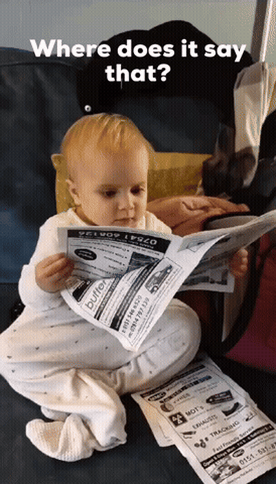 A Baby Sitting On A Couch Reading A Newspaper That Says Buffet GIF