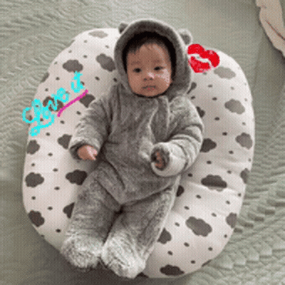 A Baby Wearing A Bear Costume Is Laying On A Pillow With A Kiss On It GIF