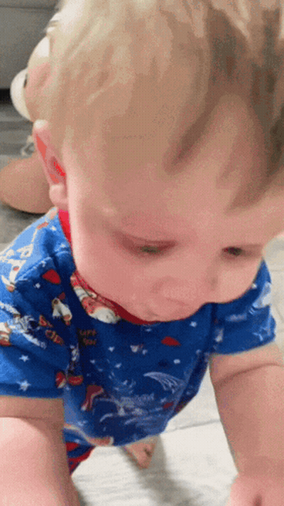 A Baby Wearing A Blue Shirt With Paw Patrol On It Is Crawling On The Floor GIF