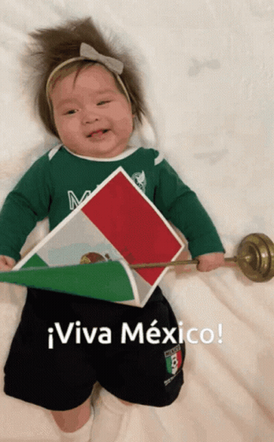 A Baby Wearing A Green Shirt And Black Shorts Is Holding A Mexican Flag And Says Viva Mexico GIF