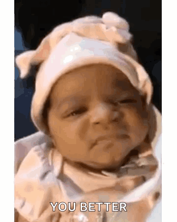 A Baby Wearing A Hat Is Sitting In A High Chair . GIF