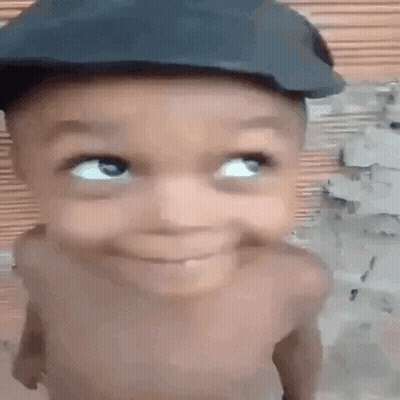 A Baby Wearing A Hat Is Smiling And Looking Up . GIF