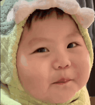 A Baby Wearing A Hat With Ears On It Is Making A Face . GIF