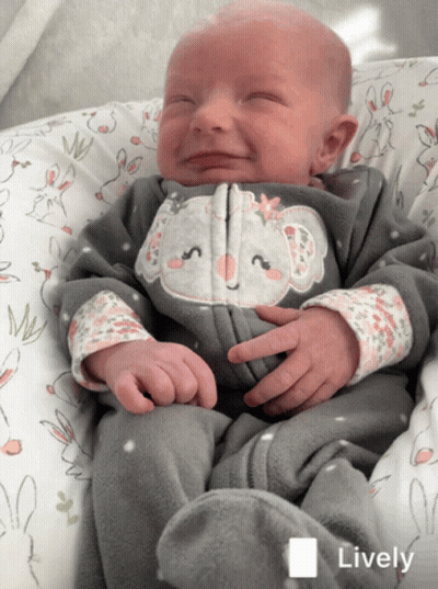 A Baby Wearing A Koala Onesie Is Smiling In A Lively Photo GIF