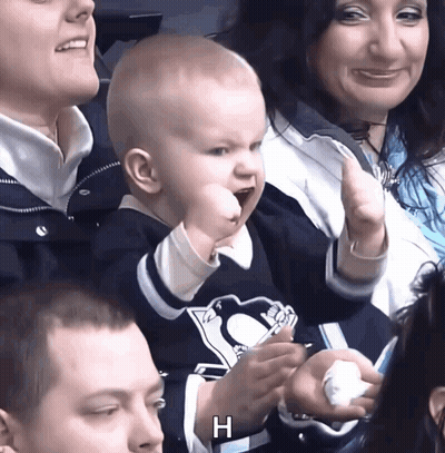 A Baby Wearing A Penguins Jersey Holds Up His Fist In The Air GIF