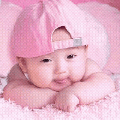 A Baby Wearing A Pink Hat Is Laying Down On A Pink Blanket GIF