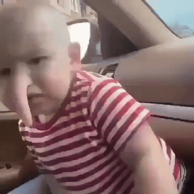 A Baby Wearing A Red And White Striped Shirt Is Sitting In The Back Seat Of A Car GIF