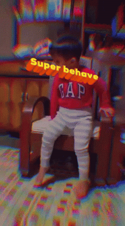 A Baby Wearing A Red Gap Sweater Sits On A Chair GIF