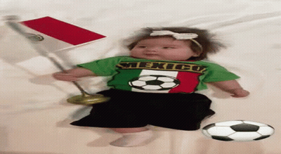 A Baby Wearing A Shirt That Says Mexico Is Laying On A Bed GIF