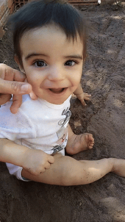 A Baby Wearing A White Shirt With A Mouse On It Smiles For The Camera GIF