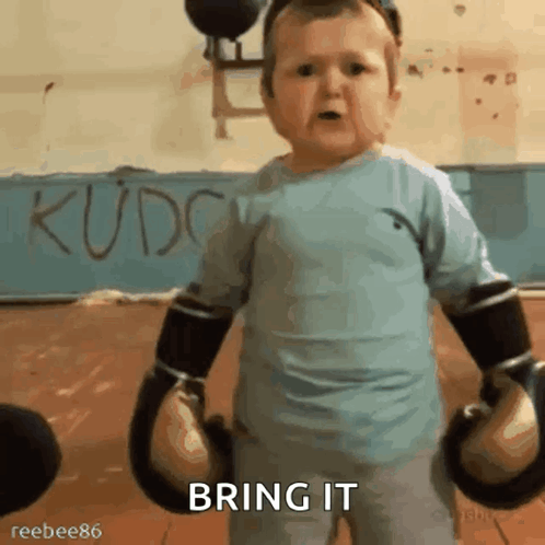 A Baby Wearing Boxing Gloves Says Bring It In A Gym GIF