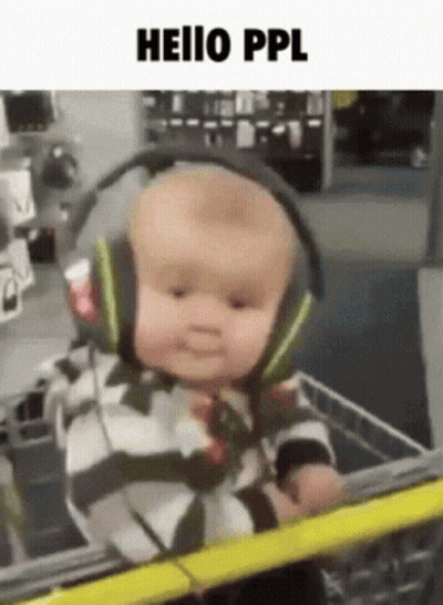 A Baby Wearing Headphones Is Sitting In A Shopping Cart GIF