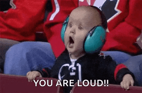 A Baby Wearing Headphones Is Sitting In A Stadium And Saying `` You Are Loud ! '' GIF