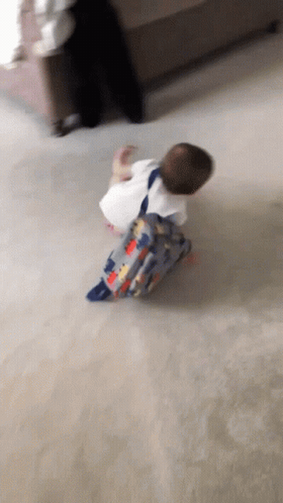 A Baby With A Backpack Is Crawling On The Floor . GIF