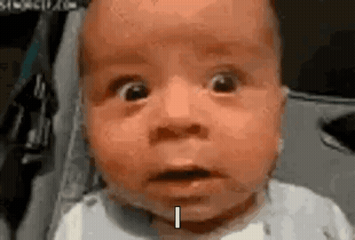 A Baby With A Surprised Look On His Face Is Sitting In A Stroller And Making A Funny Face . GIF