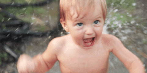A Baby Without A Shirt Is Playing In The Water And Smiling GIF