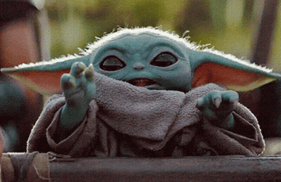 A Baby Yoda From The Mandalorian Is Sitting On A Wooden Fence . GIF