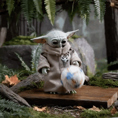 A Baby Yoda Is Holding A Soccer Ball In His Hands . GIF