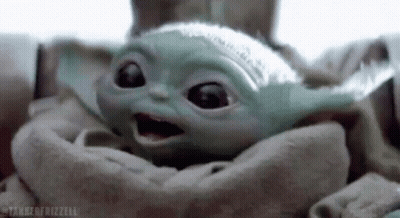 A Baby Yoda Is Sitting In A Blanket And Looking At The Camera . GIF