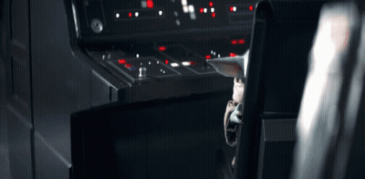 A Baby Yoda Is Sitting In A Chair In Front Of A Control Panel In A Dark Room . GIF