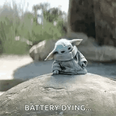 A Baby Yoda Is Sitting On Top Of A Rock With The Words `` Battery Dying '' Written On It . GIF