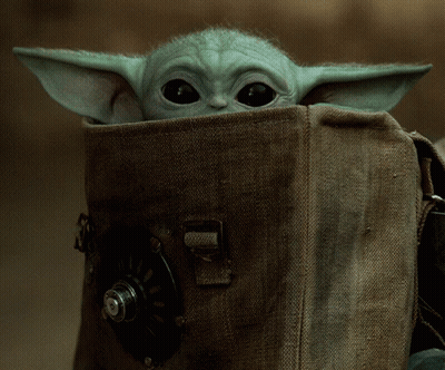 A Baby Yoda Looks Out Of A Brown Bag GIF