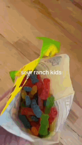 A Bag Of Sour Ranch Kids Gummy Bears Is On A Wooden Table . GIF