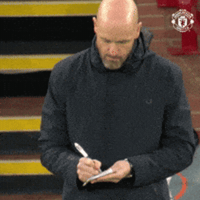 A Bald Man In A Black Jacket Is Writing On A Piece Of Paper With A Pen GIF
