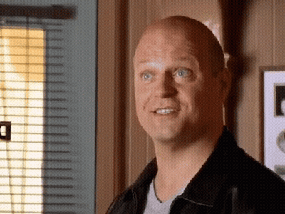 A Bald Man In A Black Jacket Looks At The Camera GIF