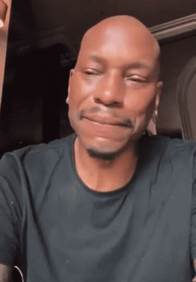 A Bald Man In A Black Shirt Is Smiling GIF