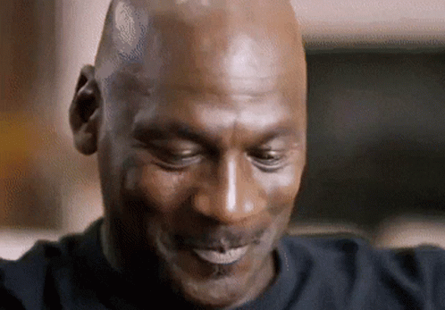 A Bald Man In A Black Shirt Is Smiling With His Eyes Closed GIF