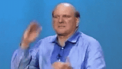 A Bald Man In A Blue Shirt Is Clapping His Hands . GIF