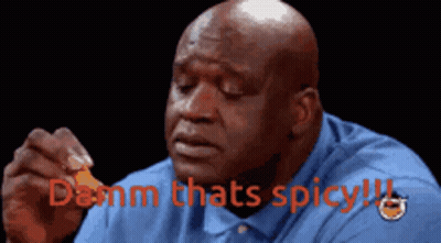 A Bald Man In A Blue Shirt Is Holding A Piece Of Food With The Words " Damn Thats Spicy " Above Him GIF
